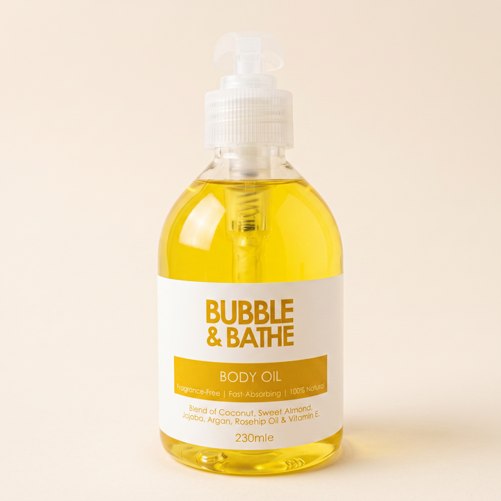 A 230ml bottle of Bubble &amp; Bathe Body Oil, filled with a golden yellow oil, featuring a white pump dispenser and a white label with gold text, set against a solid beige background.