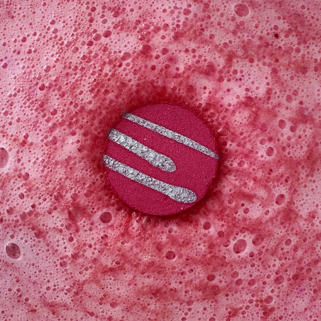 Coconut Water & Raspberry - This is a close-up image of a colourful, handmade moisturising bath bomb, designed for a relaxing spa bath experience, highlighting its natural ingredients and textured surface, perfect for aromatherapy and soothing skin.