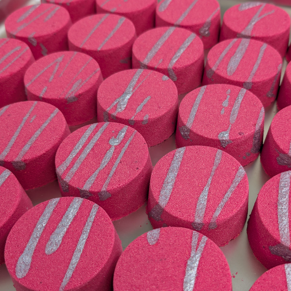 Coconut Water & Raspberry - This is a close-up image of a colourful, handmade moisturising bath bomb, designed for a relaxing spa bath experience, highlighting its natural ingredients and textured surface, perfect for aromatherapy and soothing skin.